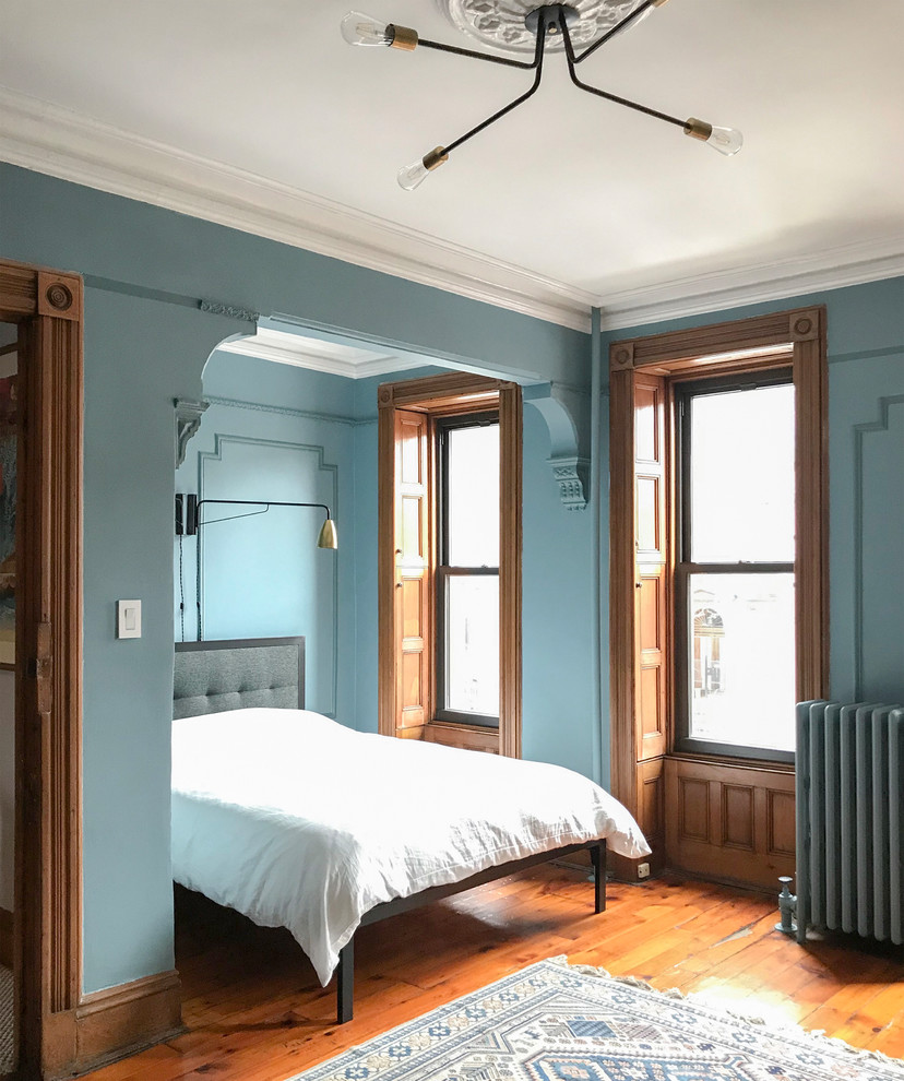 Klassisches Schlafzimmer mit blauer Wandfarbe, braunem Holzboden und braunem Boden in New York
