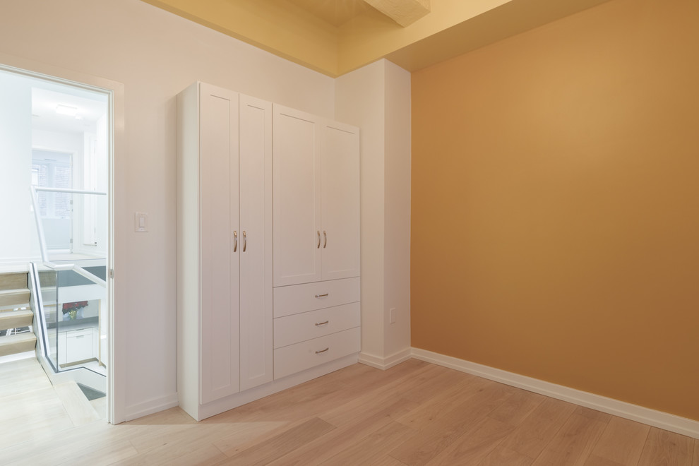 Ejemplo de dormitorio actual sin chimenea con paredes amarillas, suelo de madera clara y suelo beige