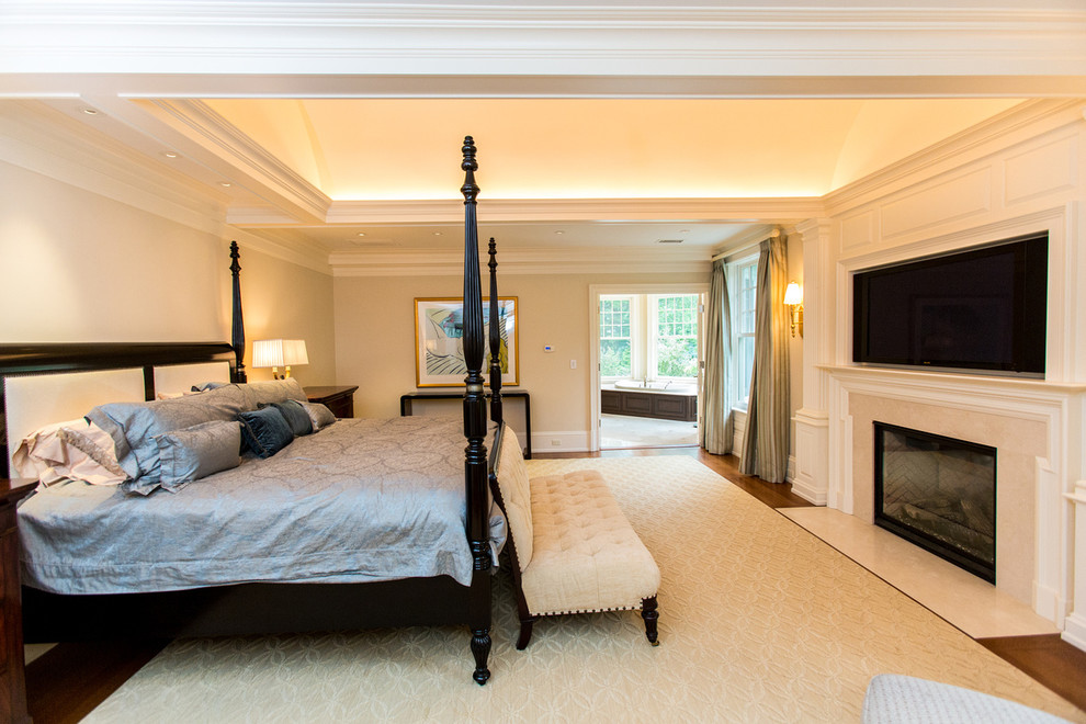 Klassisches Hauptschlafzimmer mit beiger Wandfarbe, braunem Holzboden, Kamin und Kaminumrandung aus Stein in Boston