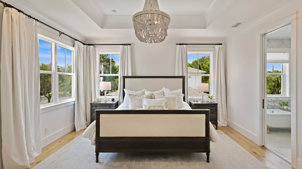 タンパにある広いトランジショナルスタイルのおしゃれな主寝室 (白い壁、無垢フローリング、ベージュの床) のインテリア
