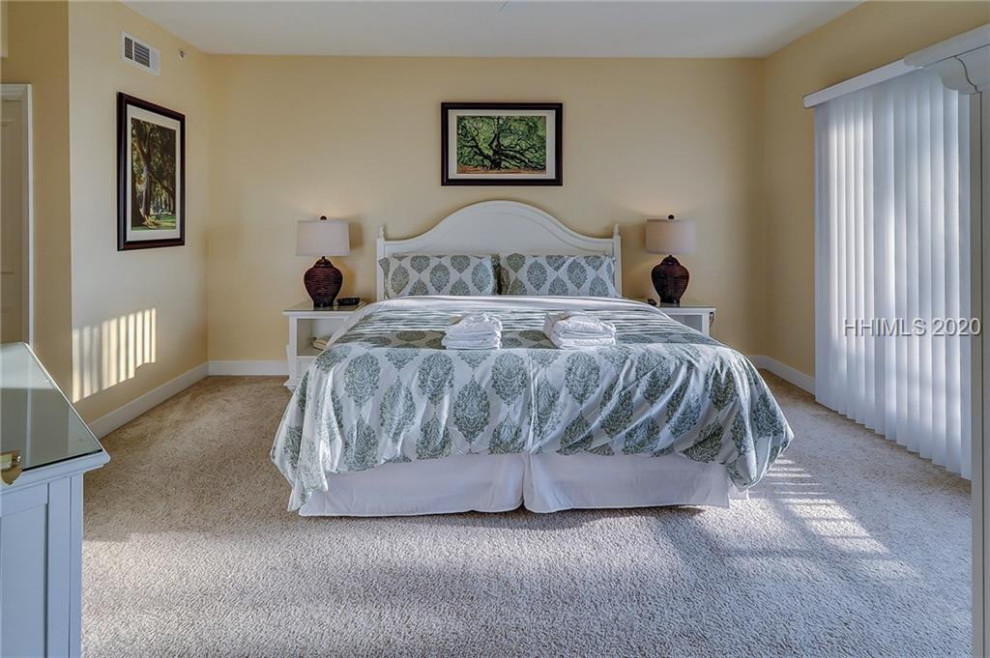 Photo of a medium sized coastal master bedroom in Other with yellow walls, carpet and beige floors.