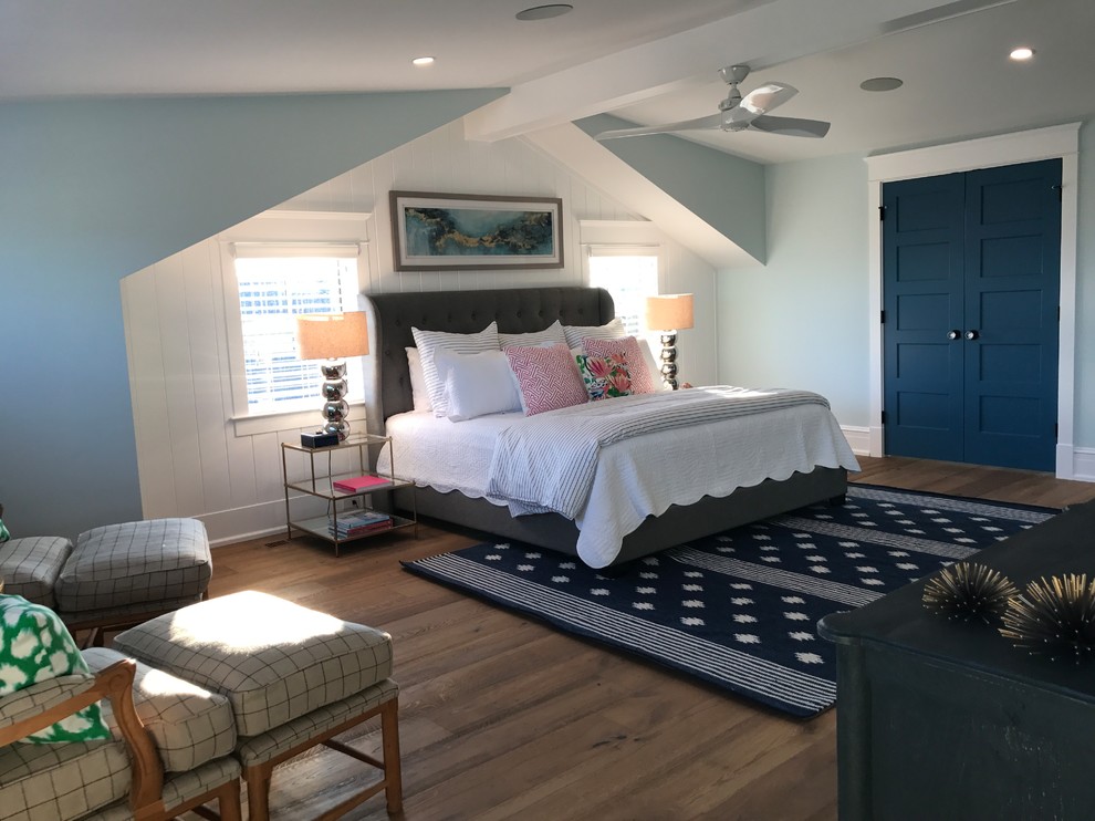 Ejemplo de dormitorio principal costero de tamaño medio con paredes azules, suelo de madera en tonos medios y suelo marrón