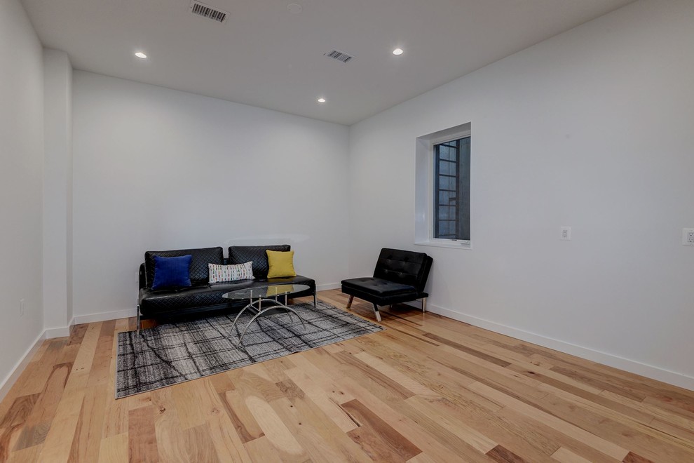 Imagen de habitación de invitados contemporánea de tamaño medio sin chimenea con paredes blancas y suelo de madera clara