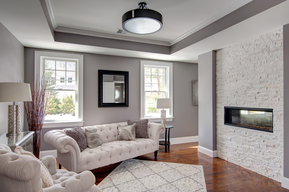 This is an example of an expansive classic guest bedroom in Boston with grey walls, dark hardwood flooring, a ribbon fireplace, a stone fireplace surround and beige floors.