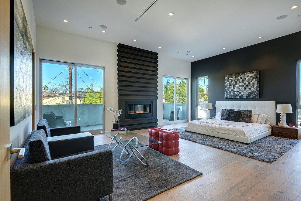Modernes Schlafzimmer mit weißer Wandfarbe, hellem Holzboden, Gaskamin und Kaminumrandung aus Metall in Los Angeles