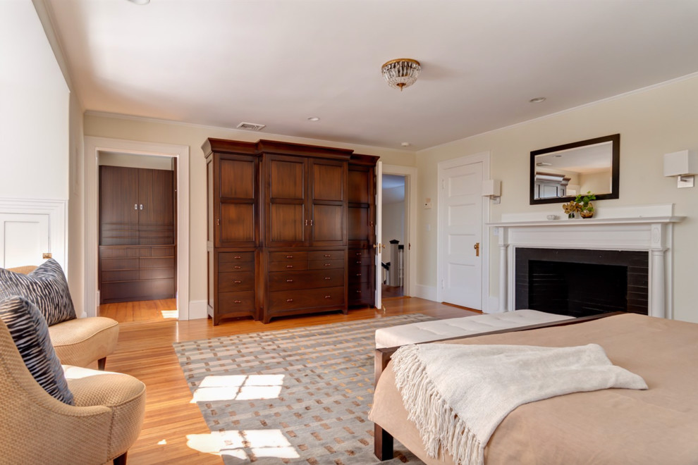 Foto de dormitorio principal tradicional renovado extra grande con paredes beige, suelo de madera en tonos medios, todas las chimeneas y marco de chimenea de madera