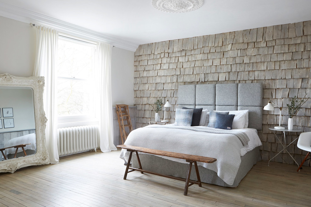 Traditional master and grey and silver bedroom in London with light hardwood flooring and a feature wall.