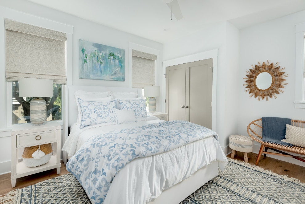 チャールストンにある広いトロピカルスタイルのおしゃれな客用寝室 (白い壁、淡色無垢フローリング、青い床) のインテリア