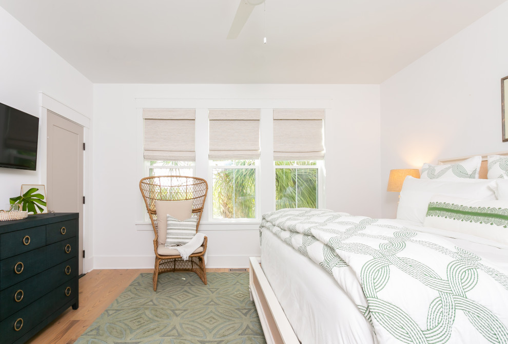 Ejemplo de habitación de invitados tropical grande con paredes blancas, suelo de madera clara y suelo azul