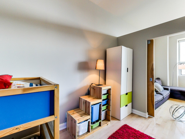 Ejemplo de habitación de invitados urbana pequeña con paredes grises y suelo de madera clara
