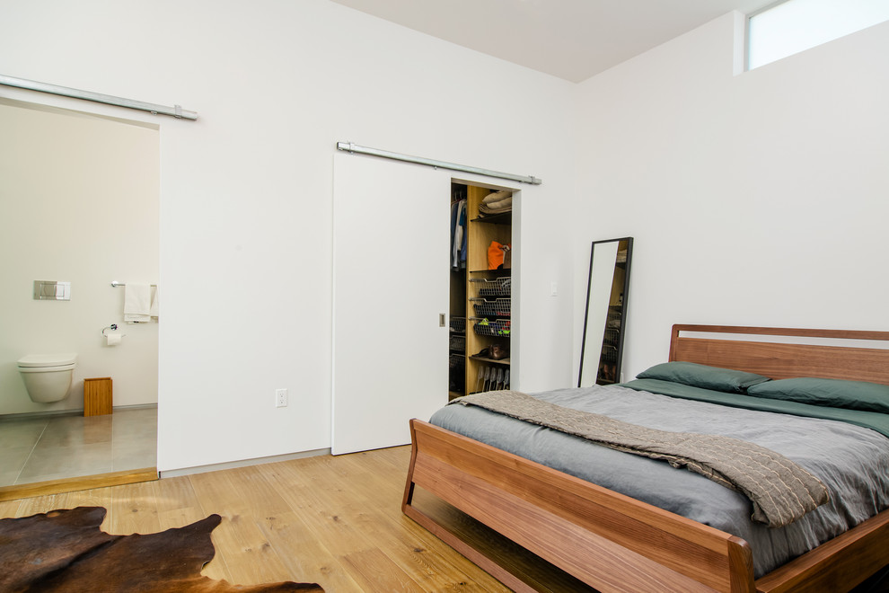 Inspiration pour une chambre parentale minimaliste avec un mur blanc et un sol en bois brun.