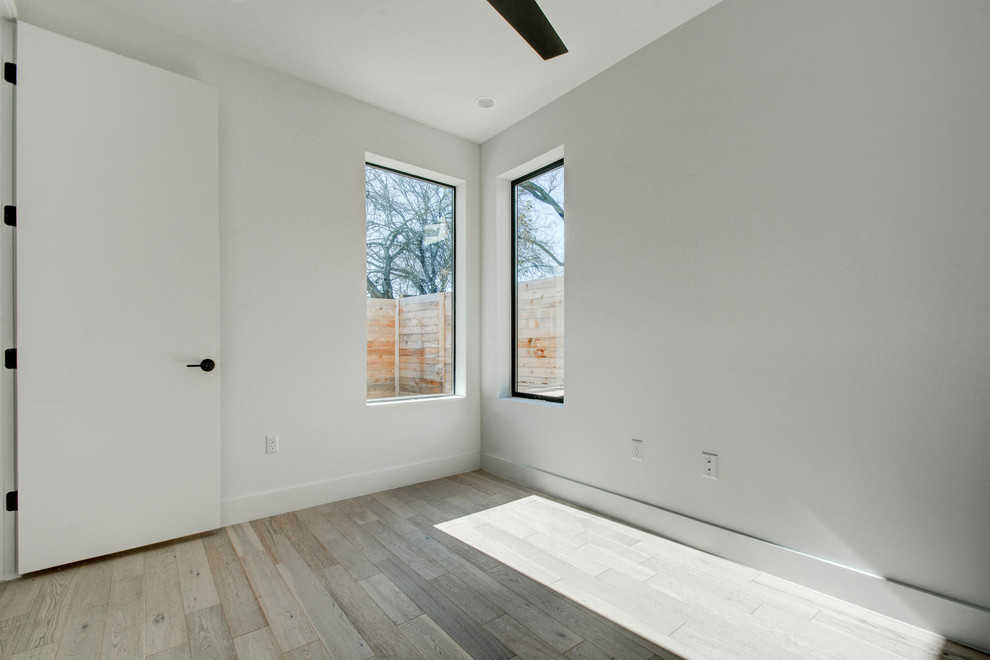 Immagine di una camera degli ospiti minimalista di medie dimensioni con pareti bianche, parquet chiaro e nessun camino