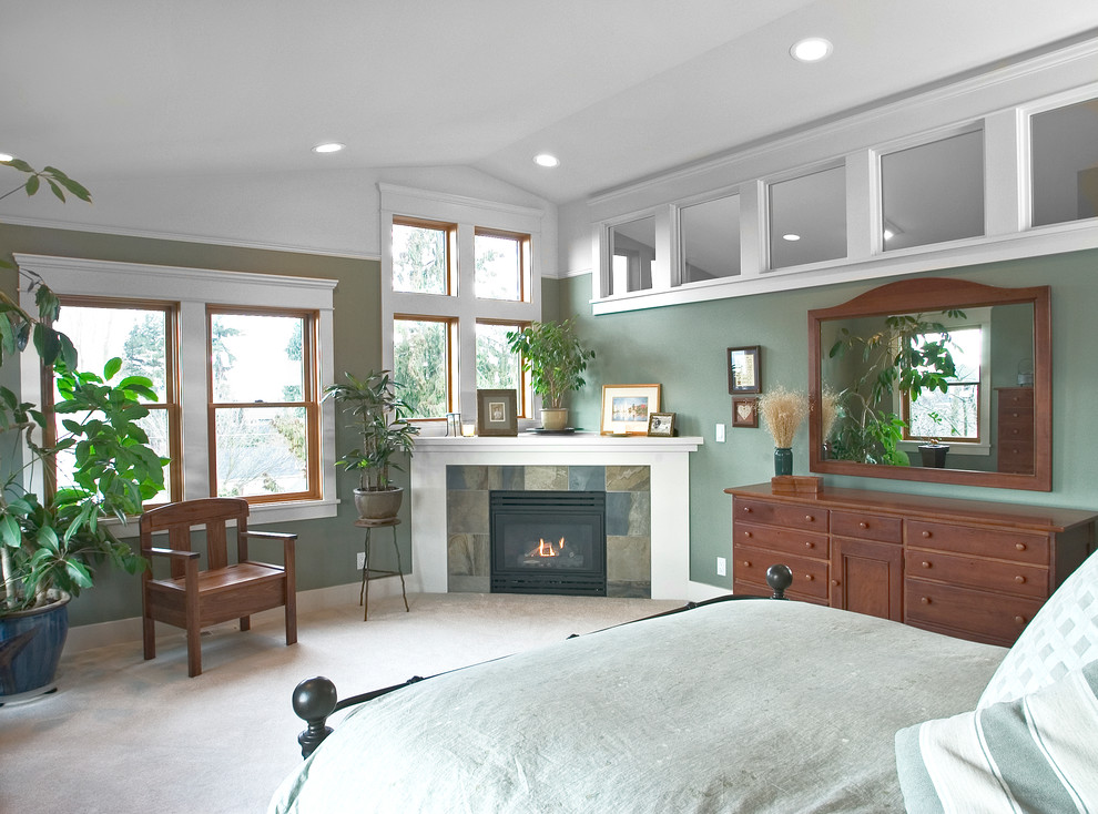 Imagen de dormitorio principal clásico grande con paredes verdes, moqueta, chimenea de esquina y marco de chimenea de piedra