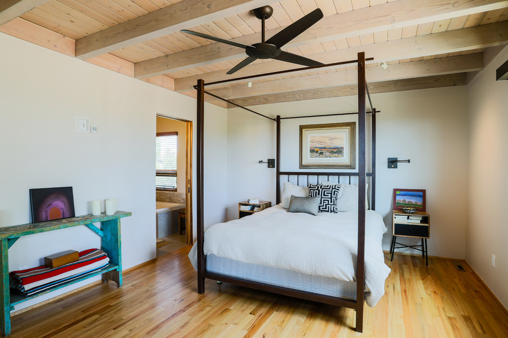 Diseño de dormitorio de estilo americano con paredes blancas, suelo de madera clara y suelo marrón