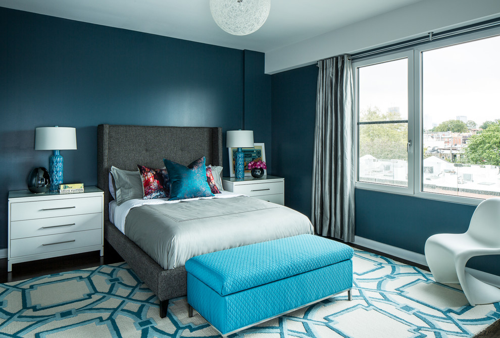Cette photo montre une chambre tendance avec un mur bleu, parquet foncé et un sol marron.