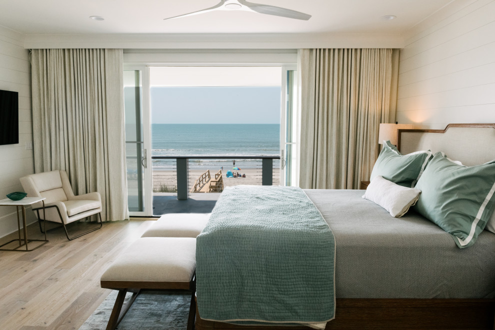 チャールストンにあるビーチスタイルのおしゃれな寝室 (白い壁、淡色無垢フローリング、暖炉なし、塗装板張りの壁)