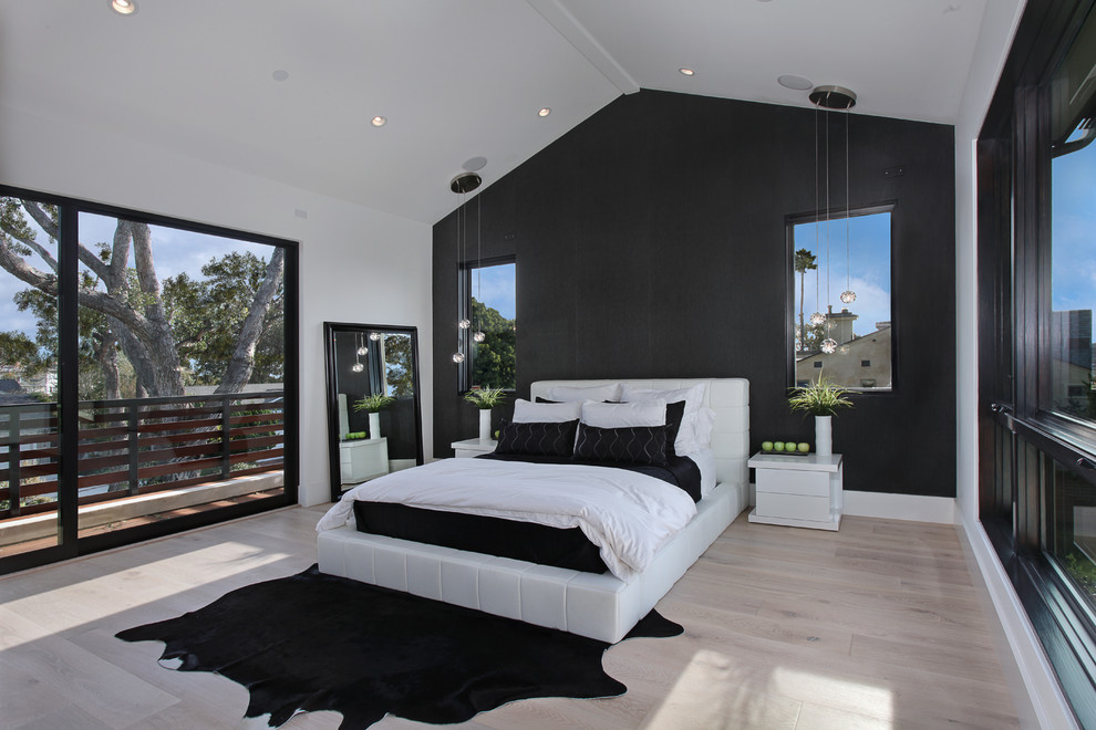 This is an example of a contemporary master bedroom in Orange County with black walls and light hardwood flooring.