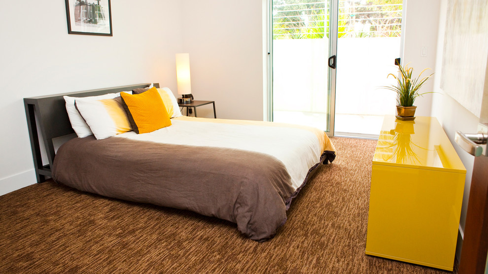 Large contemporary guest bedroom in Los Angeles with white walls and carpet.
