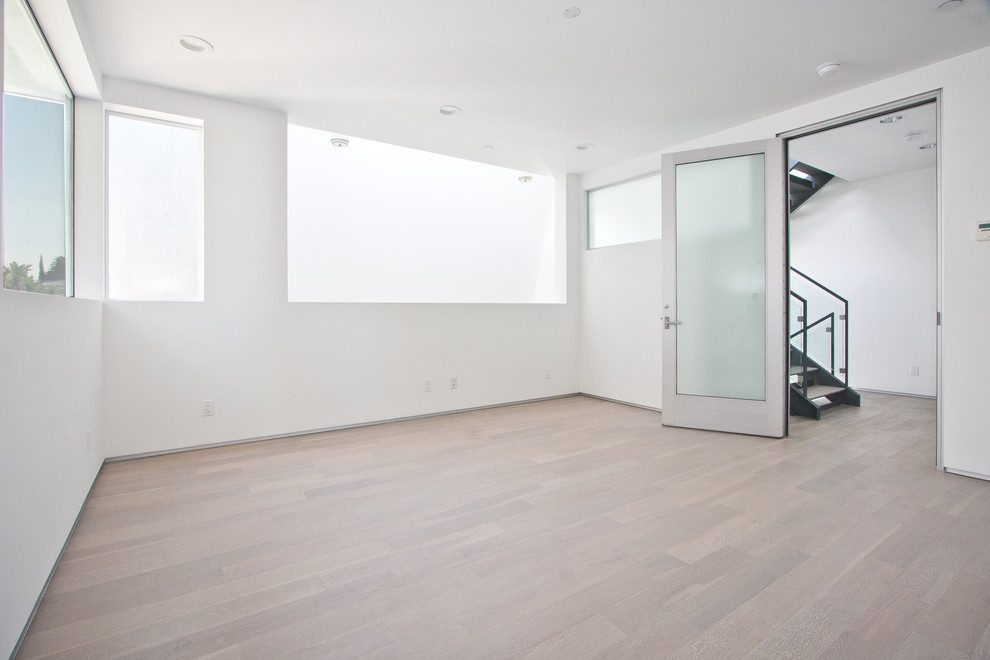 Mittelgroßes Modernes Schlafzimmer im Loft-Style mit weißer Wandfarbe, hellem Holzboden und braunem Boden in Los Angeles