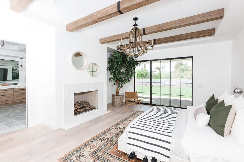 Imagen de dormitorio principal mediterráneo con paredes blancas, suelo de madera clara, todas las chimeneas y suelo beige