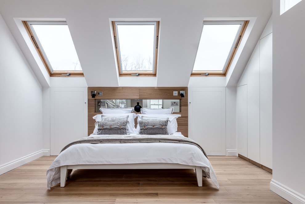 Bild på ett nordiskt sovrum, med vita väggar och mellanmörkt trägolv
