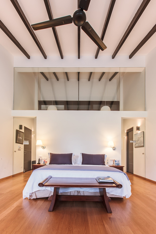 Ejemplo de dormitorio actual con paredes blancas y suelo de madera en tonos medios