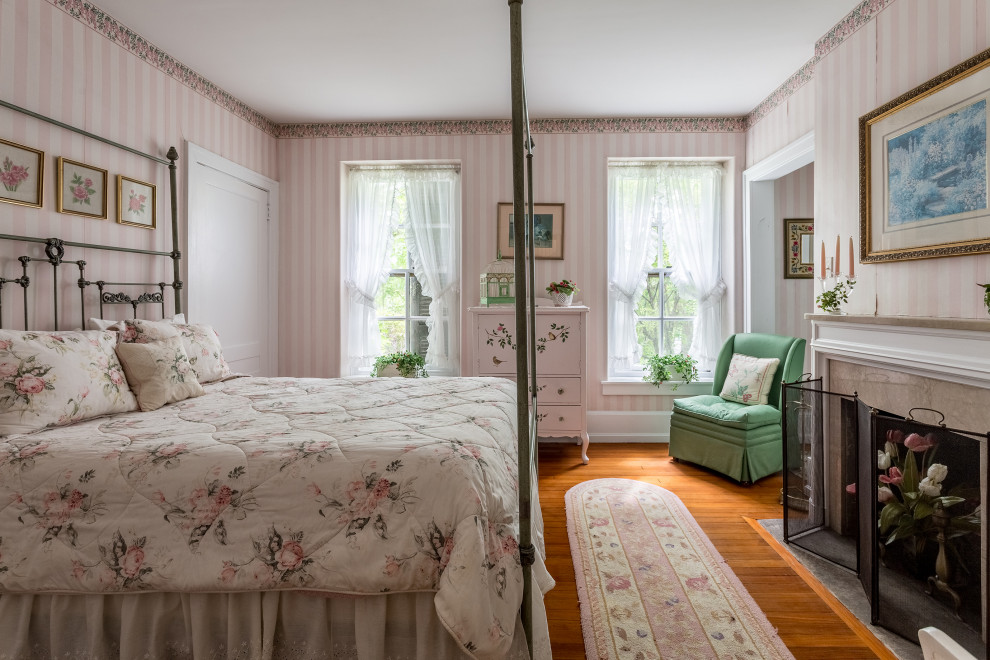 Cette image montre une grande chambre parentale traditionnelle avec un mur rose, un sol en bois brun, une cheminée standard, un manteau de cheminée en carrelage, un sol marron et du papier peint.