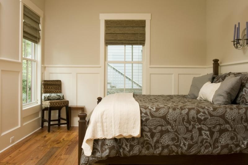 Klassisk inredning av ett sovrum, med beige väggar och mellanmörkt trägolv