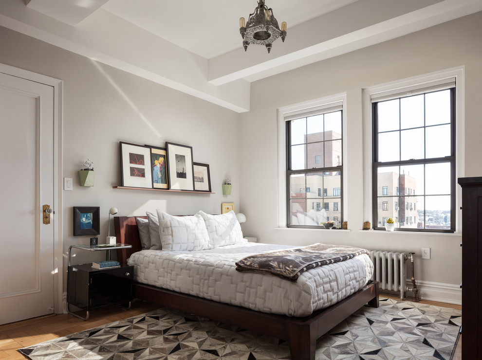 Modelo de dormitorio principal clásico renovado grande sin chimenea con paredes grises, suelo de madera en tonos medios y suelo marrón
