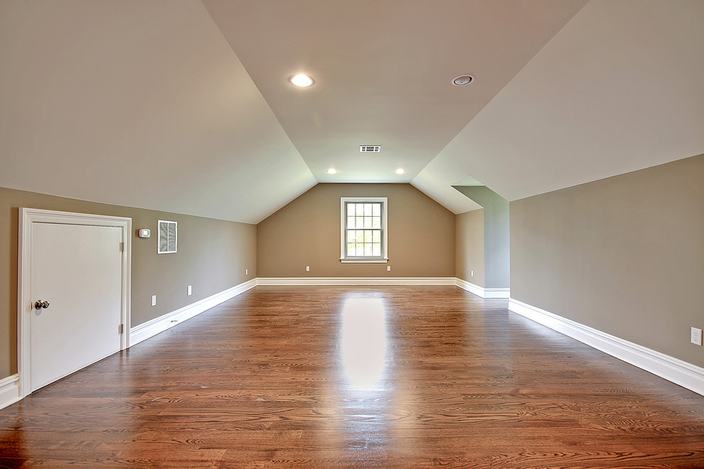 Cette image montre une très grande chambre mansardée ou avec mezzanine traditionnelle avec un mur beige et un sol en bois brun.