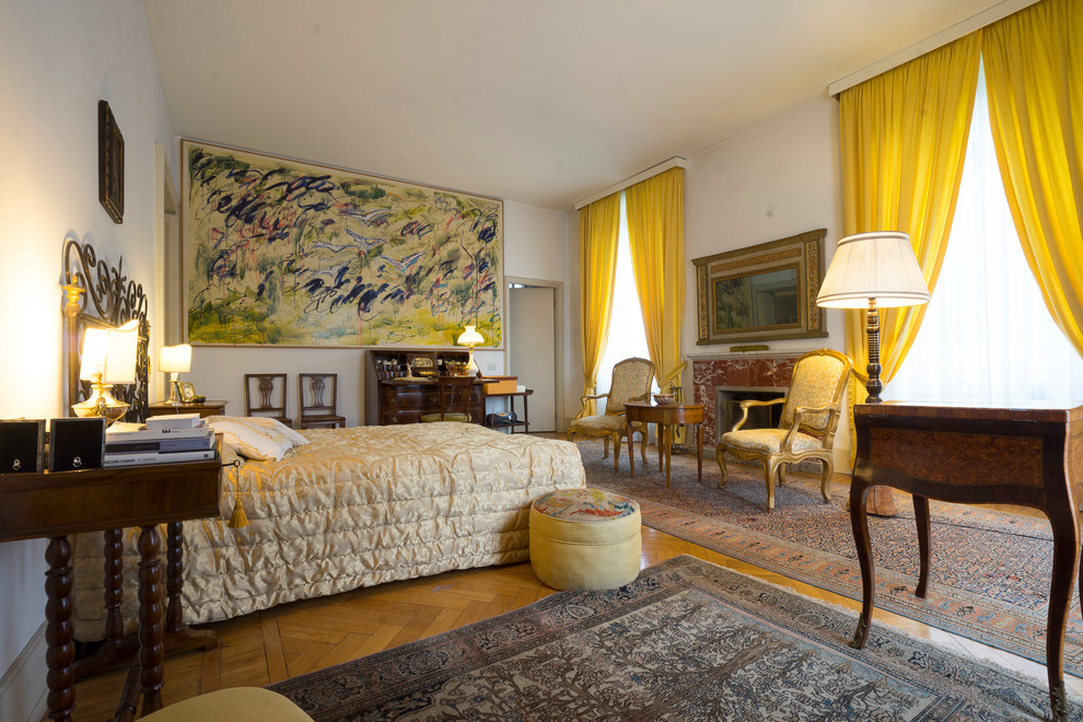 ミラノにある巨大なトラディショナルスタイルのおしゃれな主寝室 (白い壁、淡色無垢フローリング、標準型暖炉、石材の暖炉まわり)