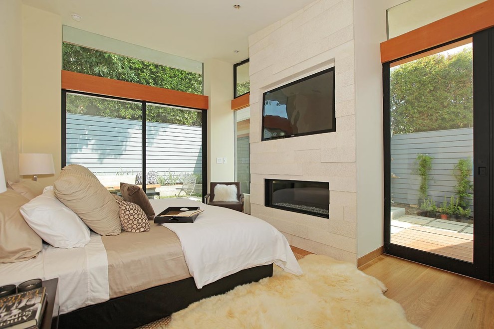 Aménagement d'une chambre contemporaine avec un mur beige, un sol en bois brun, une cheminée ribbon et un manteau de cheminée en pierre.