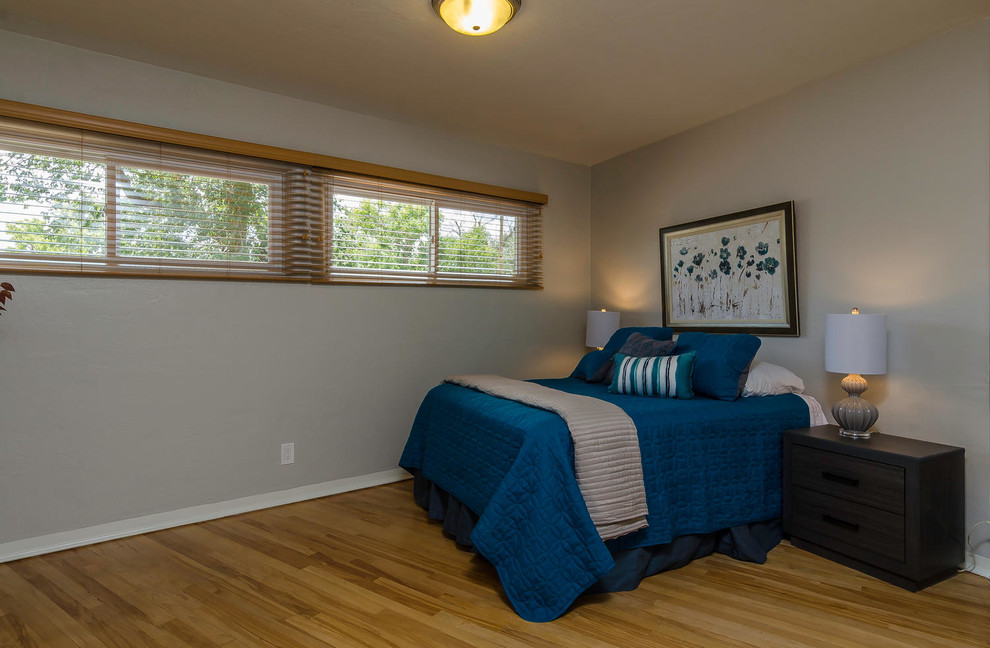 Imagen de habitación de invitados de estilo americano pequeña sin chimenea con paredes grises y suelo de madera clara