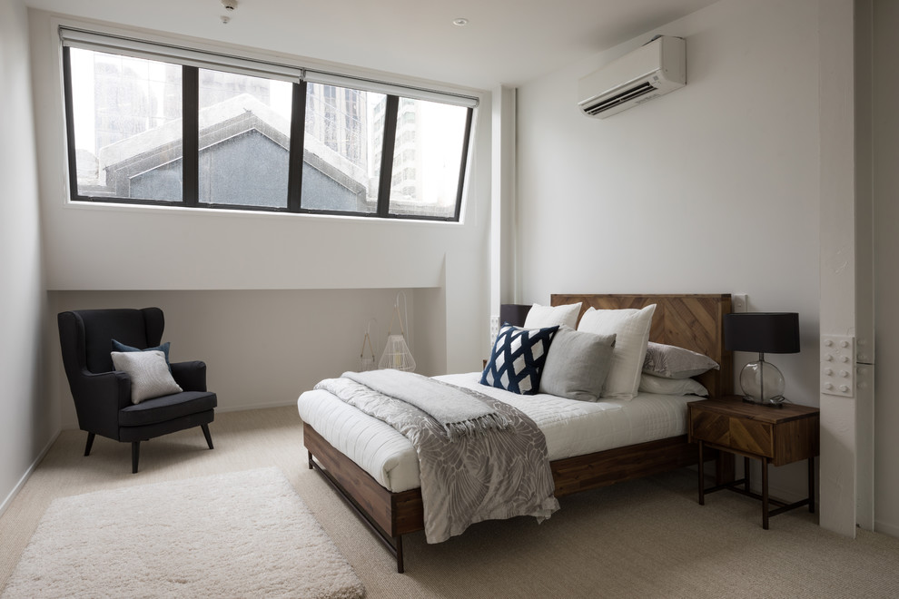Large industrial guest bedroom in Auckland with white walls, carpet and beige floors.