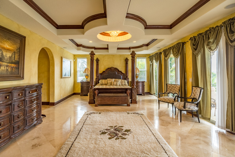 Esempio di un'ampia camera matrimoniale mediterranea con pareti gialle, pavimento in marmo, nessun camino e pavimento beige