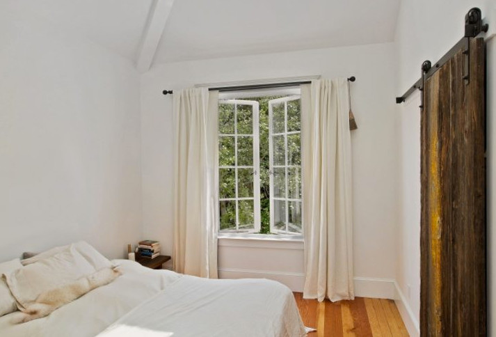 Ejemplo de dormitorio campestre de tamaño medio con paredes blancas y suelo de madera en tonos medios