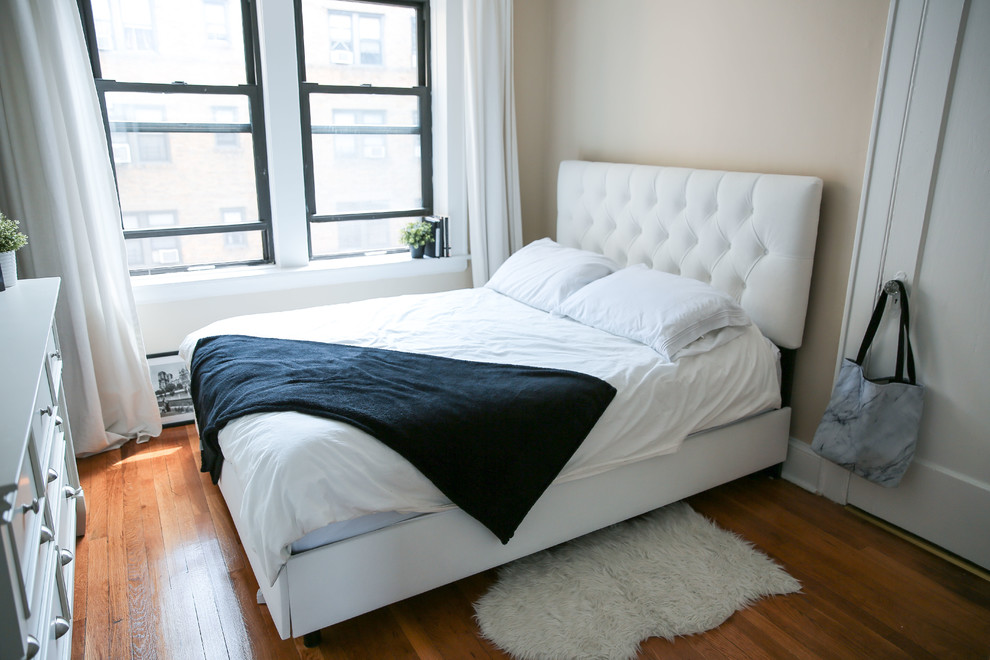 Kleines Modernes Schlafzimmer im Loft-Style mit beiger Wandfarbe, braunem Holzboden und braunem Boden in New York