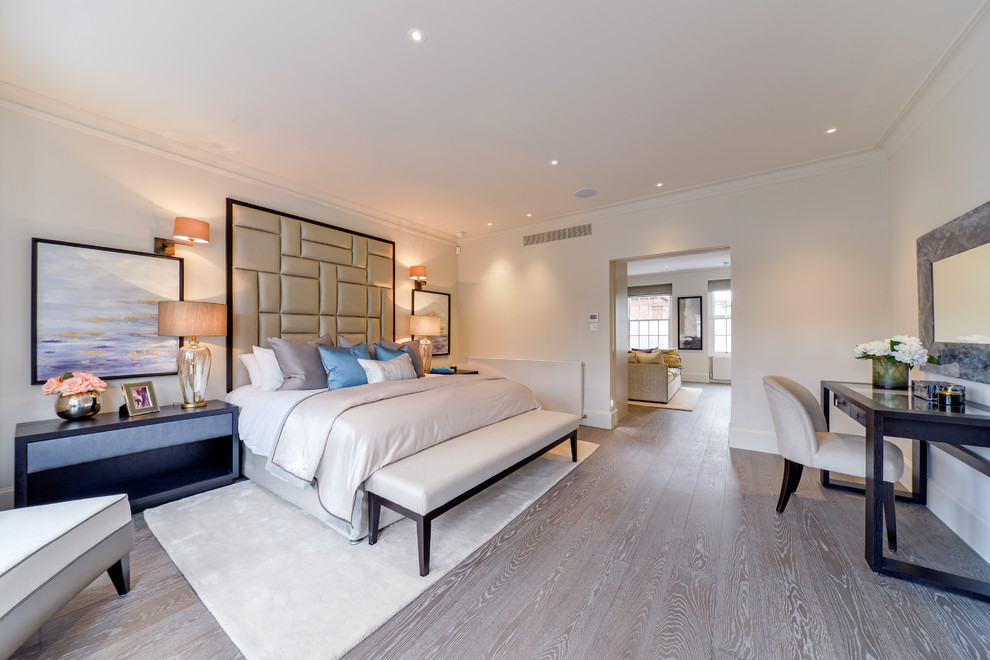 This is an example of a large traditional master bedroom in London with beige walls, medium hardwood flooring and beige floors.