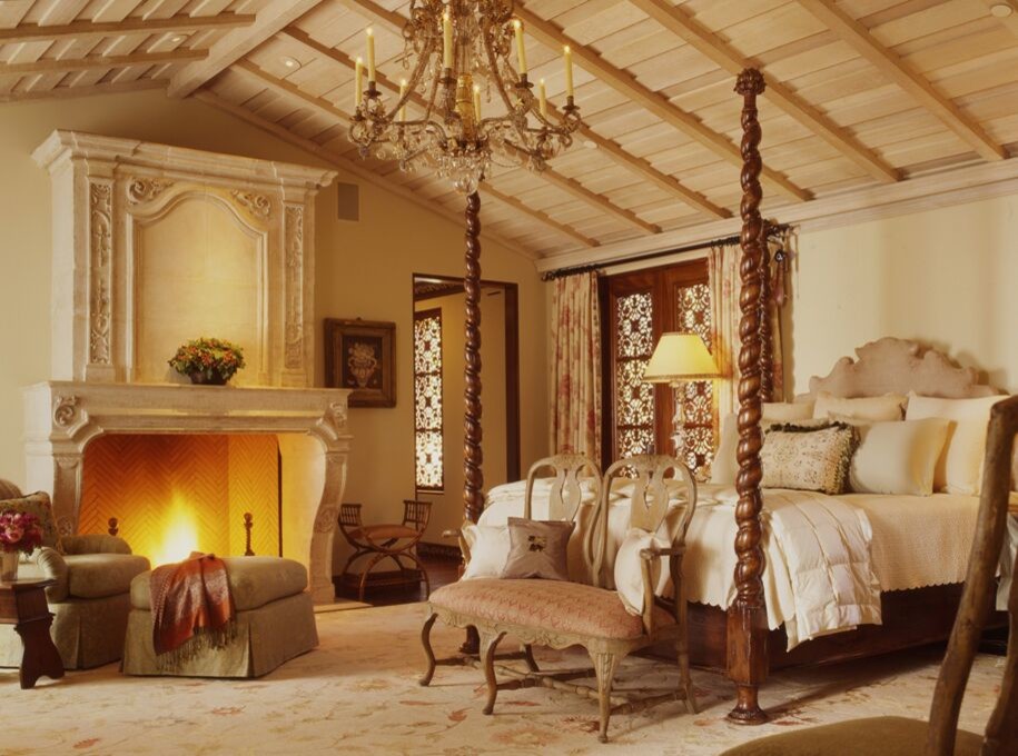 Aménagement d'une grande chambre parentale méditerranéenne avec un mur blanc, parquet foncé, une cheminée standard, un manteau de cheminée en pierre et un sol beige.