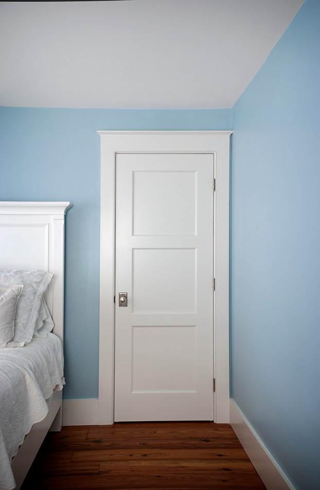 ボストンにある広いビーチスタイルのおしゃれな主寝室 (青い壁、濃色無垢フローリング、横長型暖炉、漆喰の暖炉まわり、茶色い床)