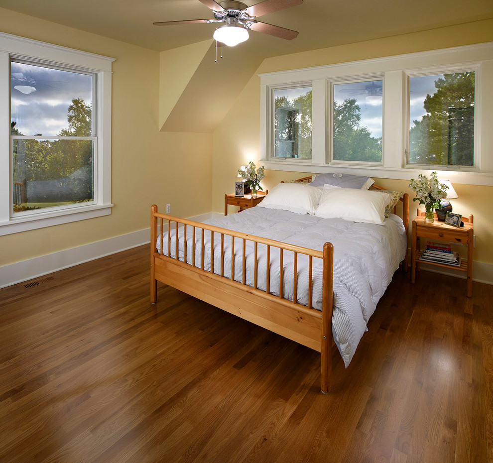 Aménagement d'une chambre d'amis classique de taille moyenne avec un mur jaune, un sol en bois brun et un sol marron.