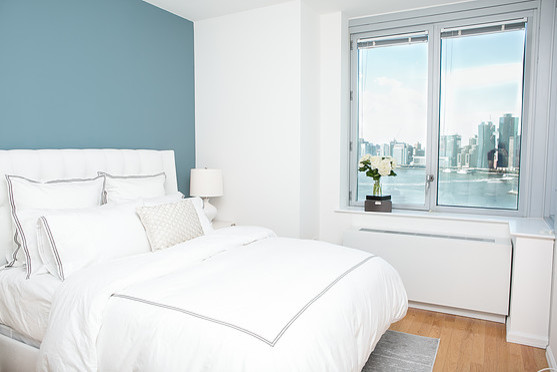 Immagine di una camera matrimoniale moderna di medie dimensioni con pareti blu e parquet chiaro