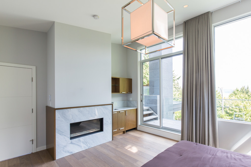 Idée de décoration pour une grande chambre parentale minimaliste avec un mur blanc, un sol en bois brun, une cheminée standard, un manteau de cheminée en carrelage et un sol marron.