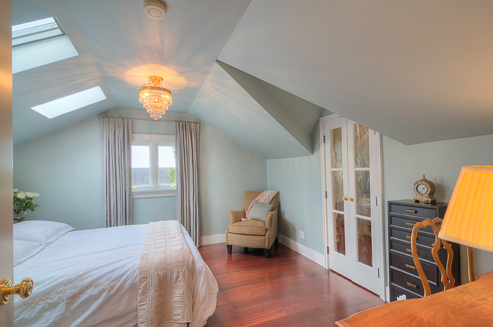 Modelo de dormitorio principal clásico de tamaño medio sin chimenea con paredes azules y suelo de madera en tonos medios
