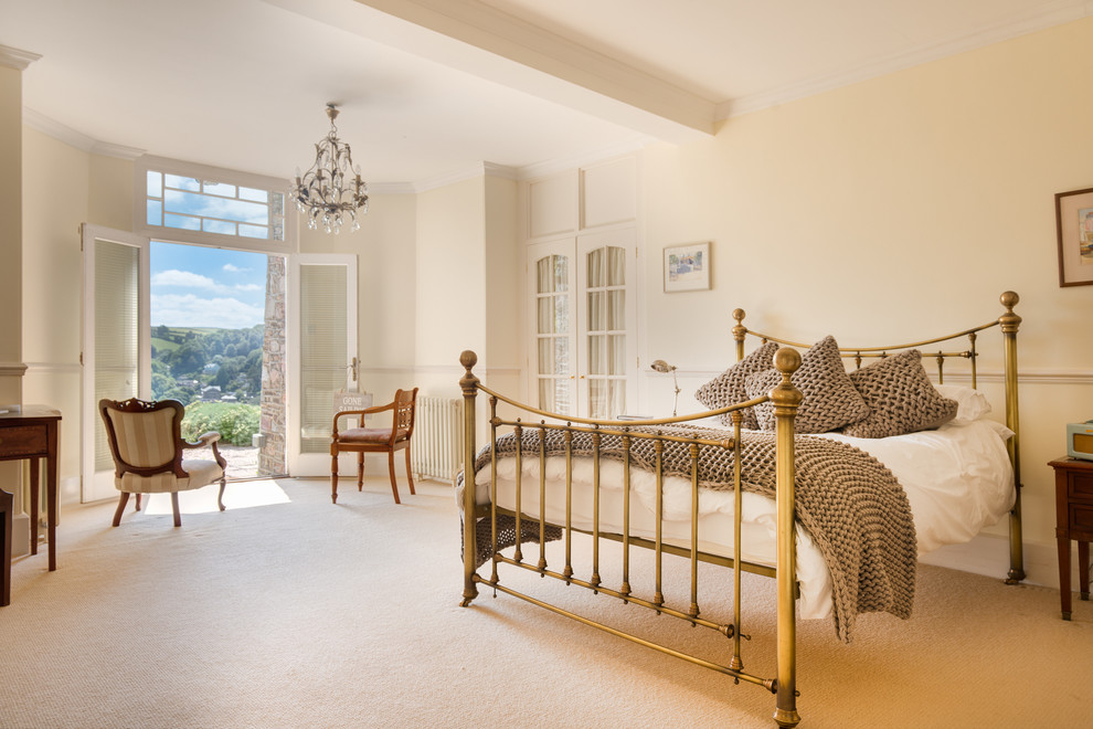 Large cottage master carpeted bedroom photo in Devon with beige walls