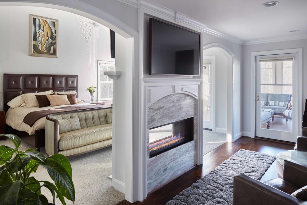 Mittelgroßes Klassisches Hauptschlafzimmer mit grauer Wandfarbe, dunklem Holzboden, braunem Boden, Tunnelkamin und Kaminumrandung aus Stein in Raleigh