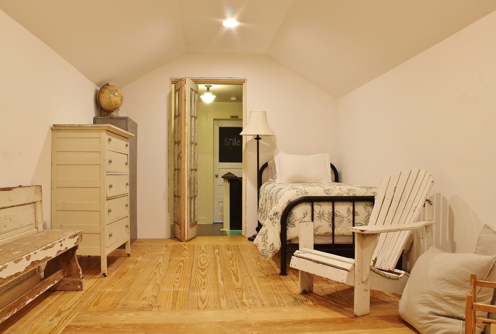Lantlig inredning av ett sovrum, med vita väggar och mellanmörkt trägolv