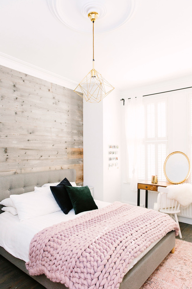 Mittelgroßes Rustikales Hauptschlafzimmer mit weißer Wandfarbe, dunklem Holzboden, Kamin, Kaminumrandung aus Stein und braunem Boden in London