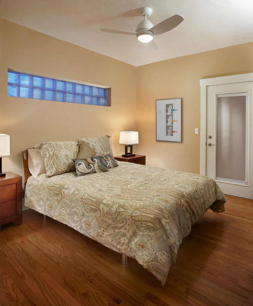 Foto di una camera degli ospiti minimal con pareti beige, pavimento in legno massello medio e nessun camino
