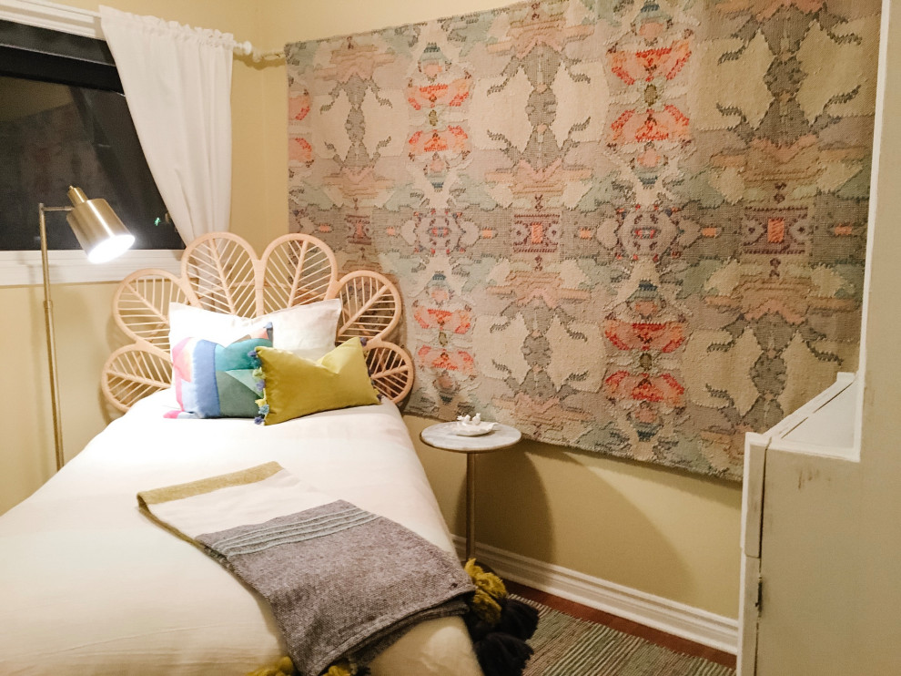 Modelo de habitación de invitados ecléctica pequeña con paredes amarillas y suelo de madera en tonos medios